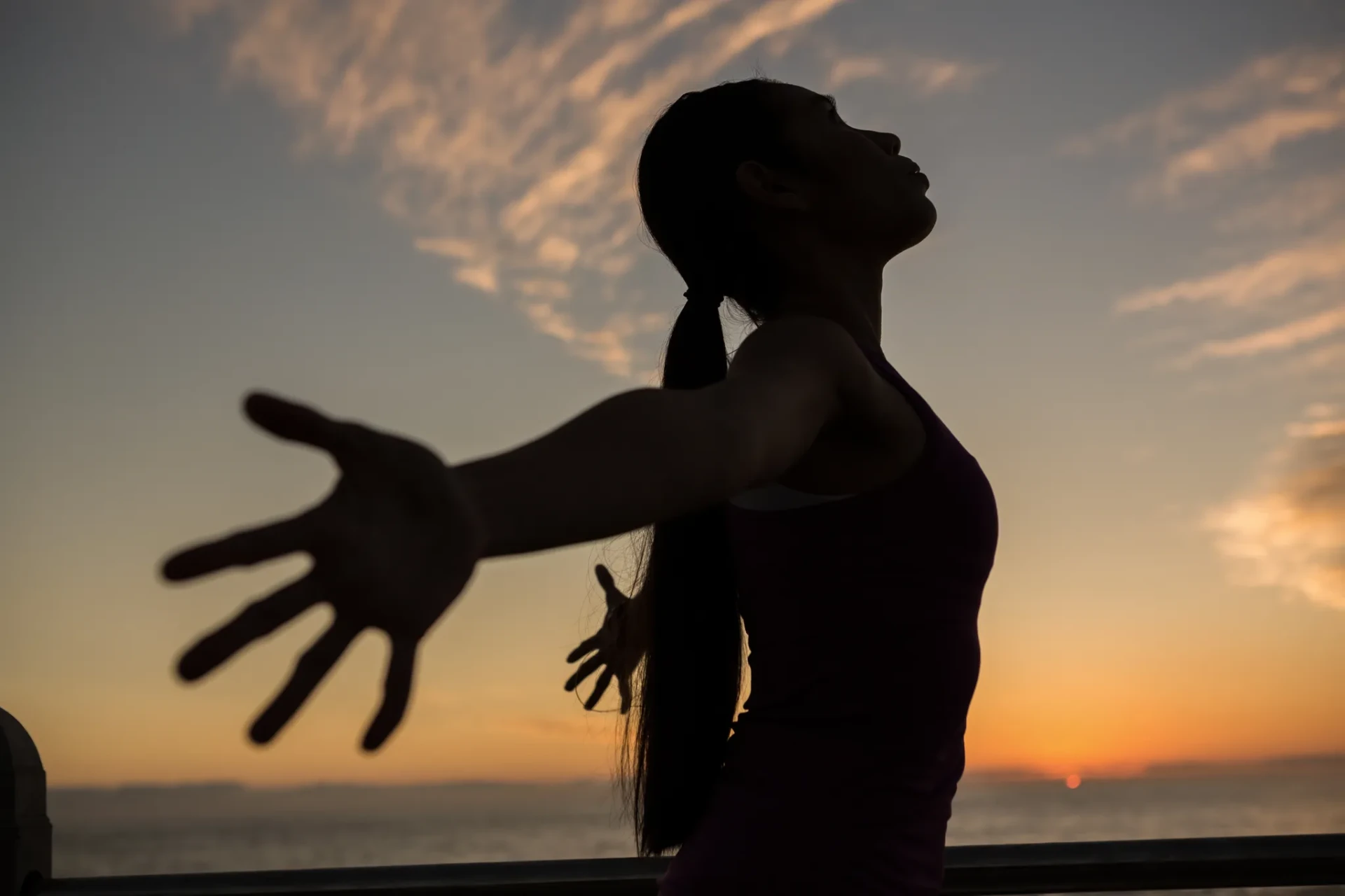 Person stretching arms open at sunrise